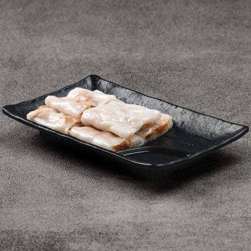 Rice noodle rolls on a black rectangular plate against a gray background