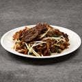 Plated dish of noodles with meat and vegetables on a gray background