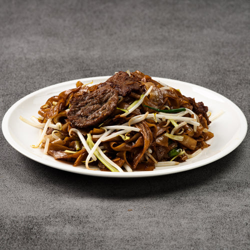 Plated dish of noodles with meat and vegetables on a gray background