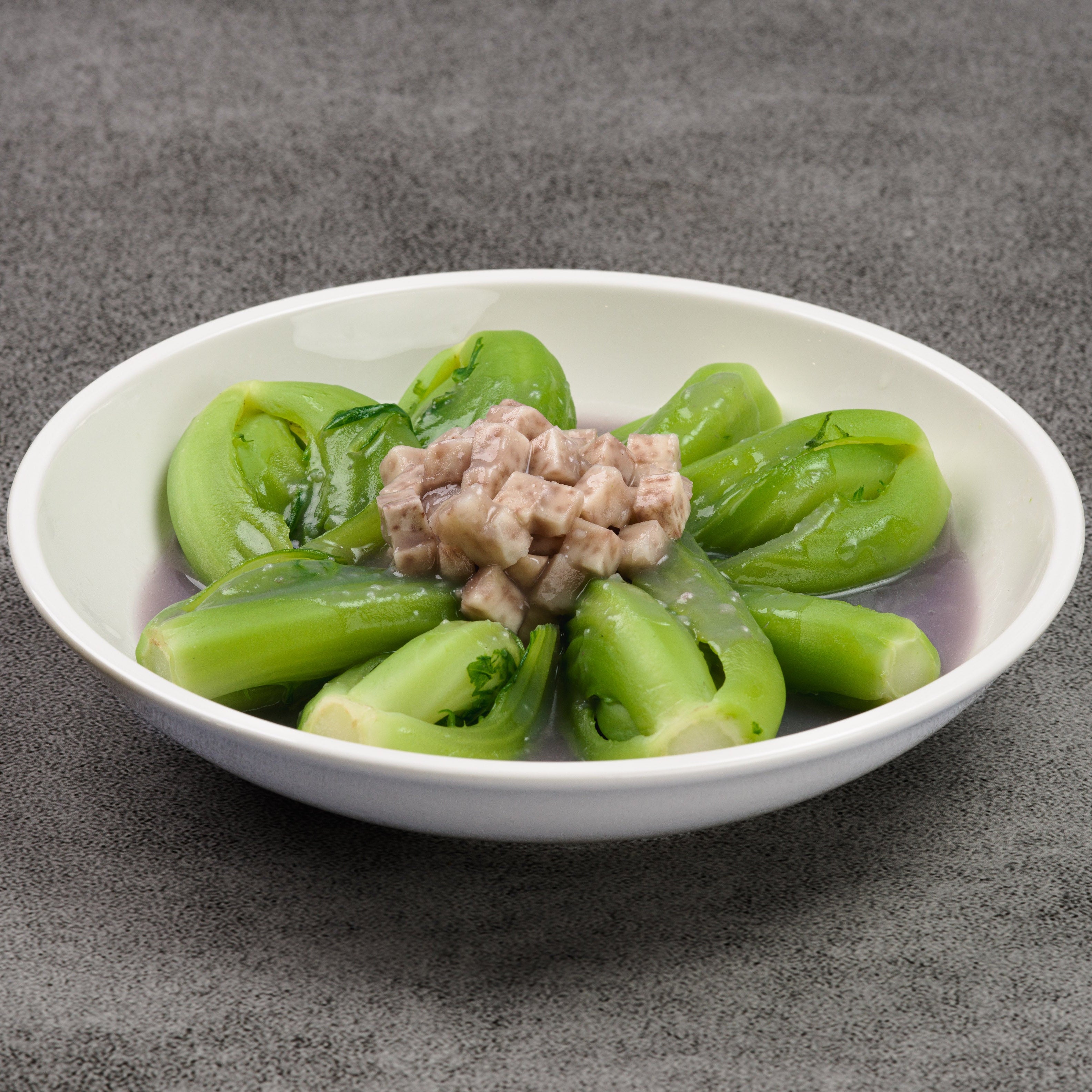 White bowl with green vegetables and minced taro on a gray background