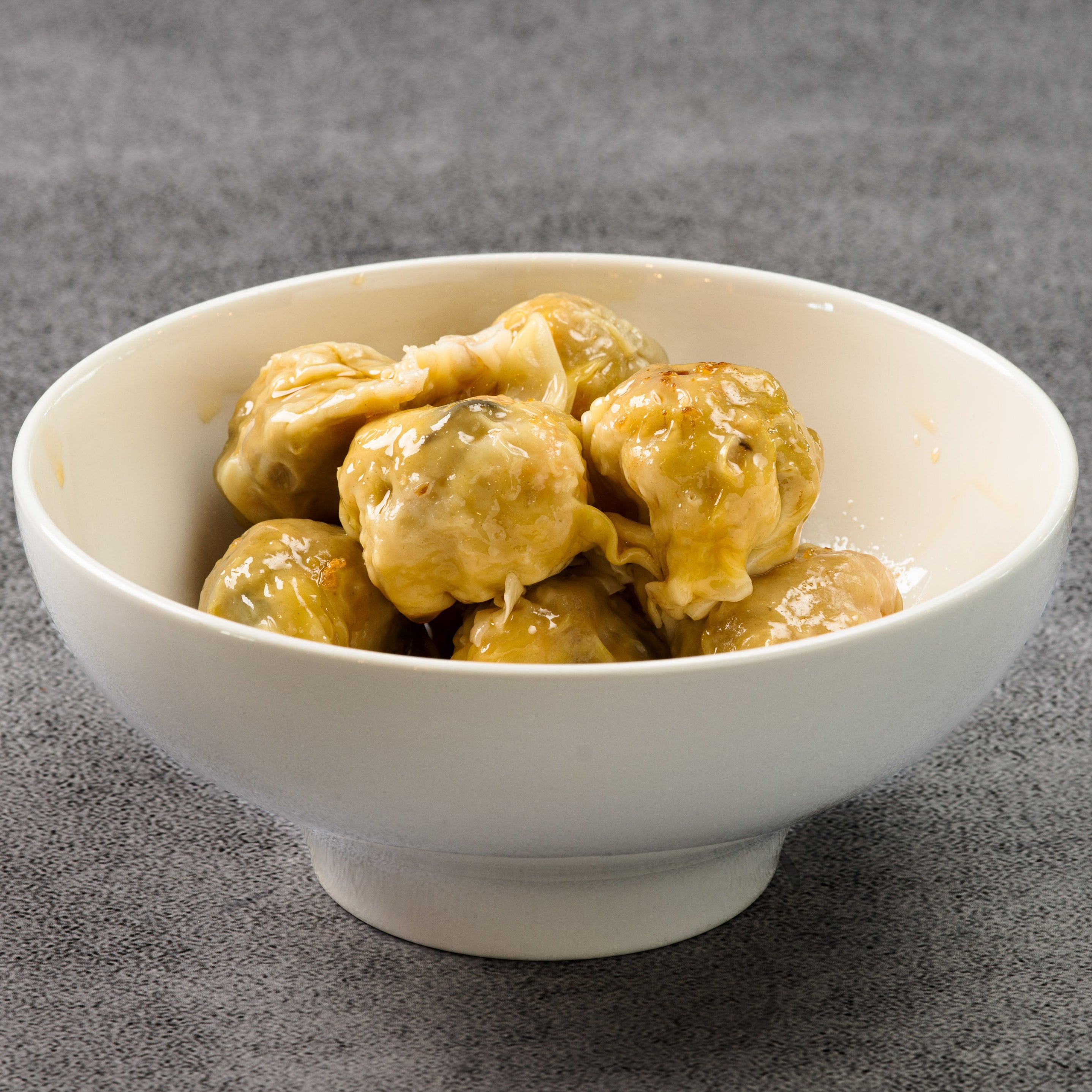 White bowl filled with wontons on a gray background