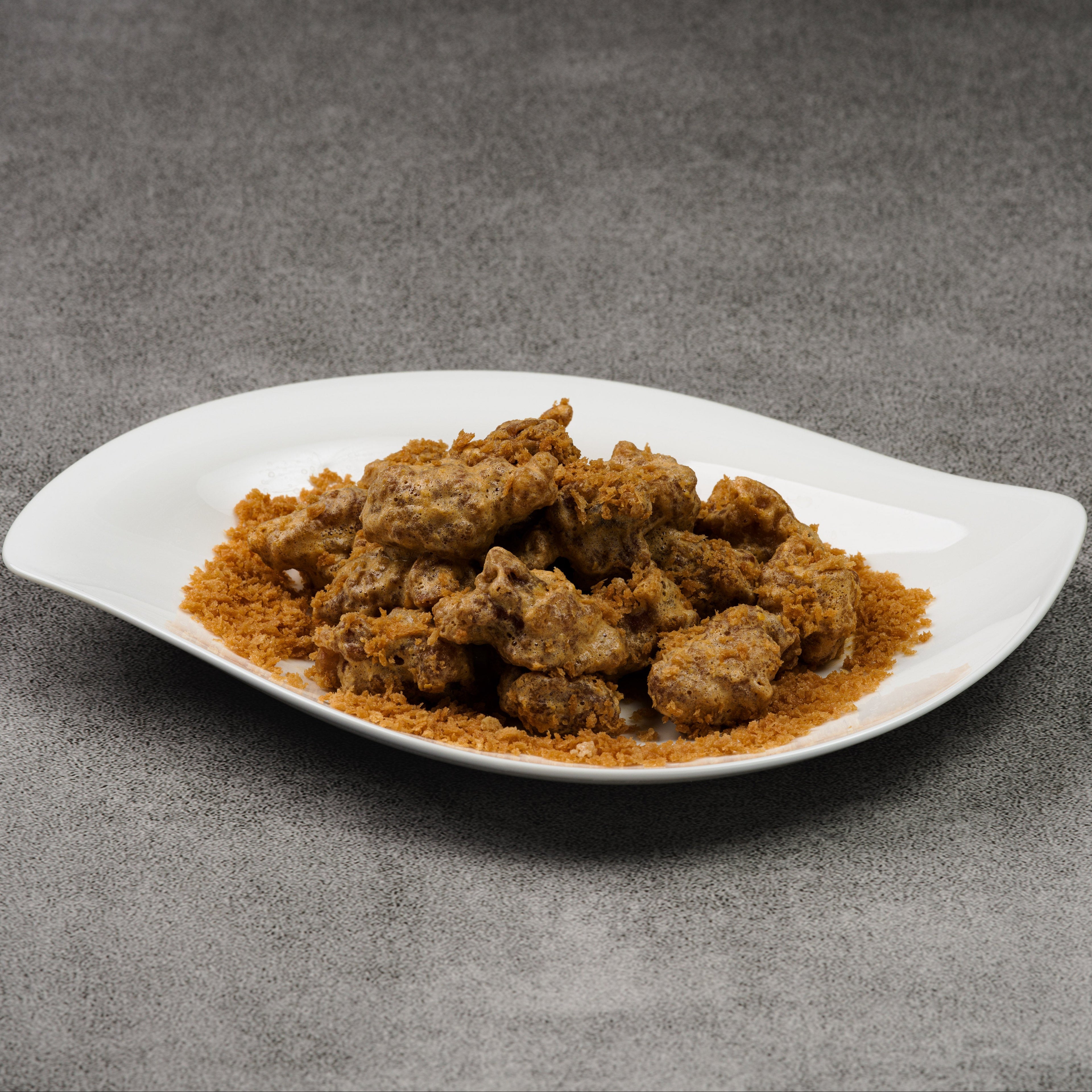 White plate with fried pork pieces on a gray background