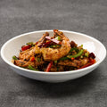 White bowl filled with crispy shrimp dish on a gray background