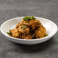 Fried chicken with green onions on a white plate against a gray background