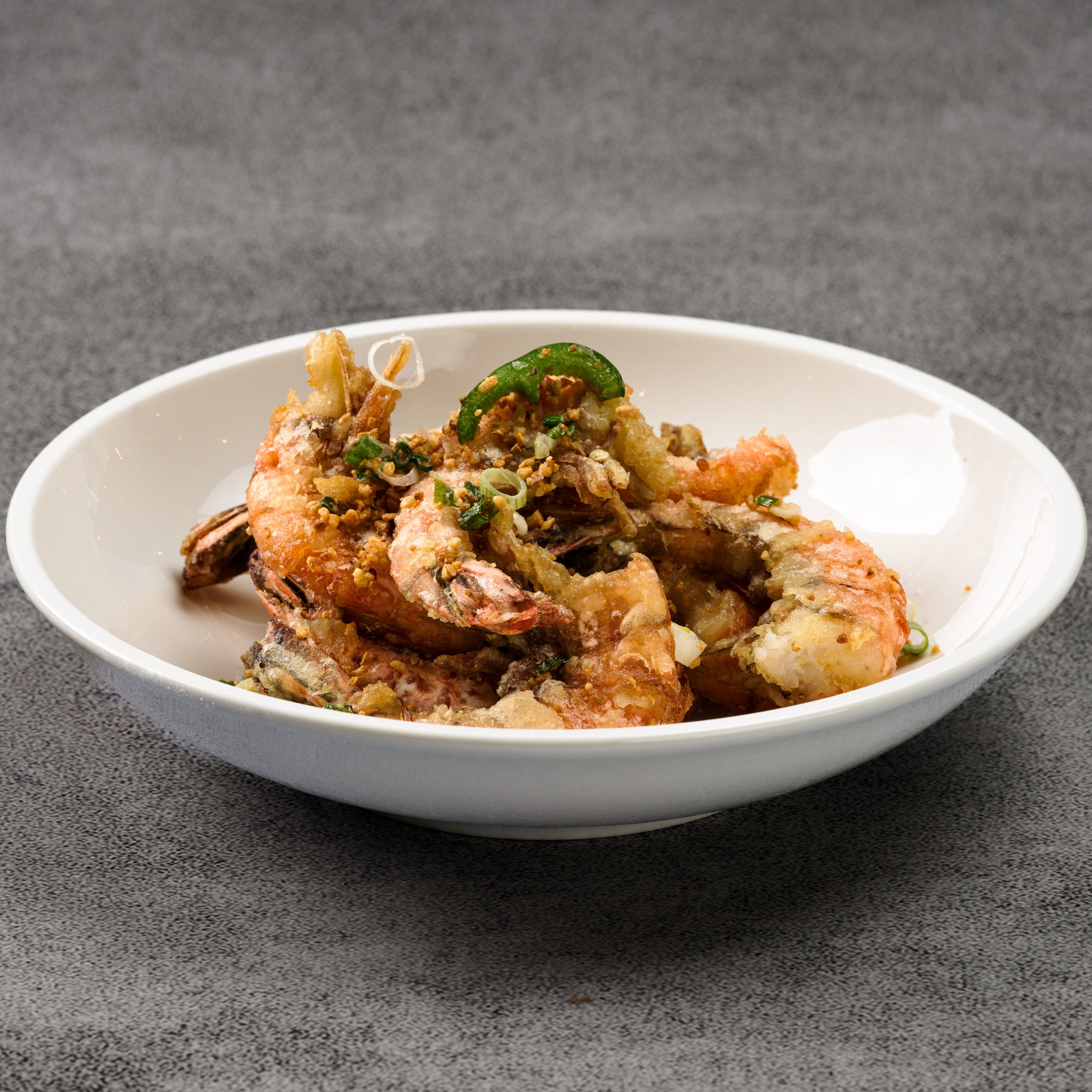White bowl with fried shrimp on a gray background