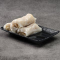 Rice noodle rolls on a black rectangular plate against a gray background