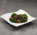 White bowl with beef and broccoli on a gray background