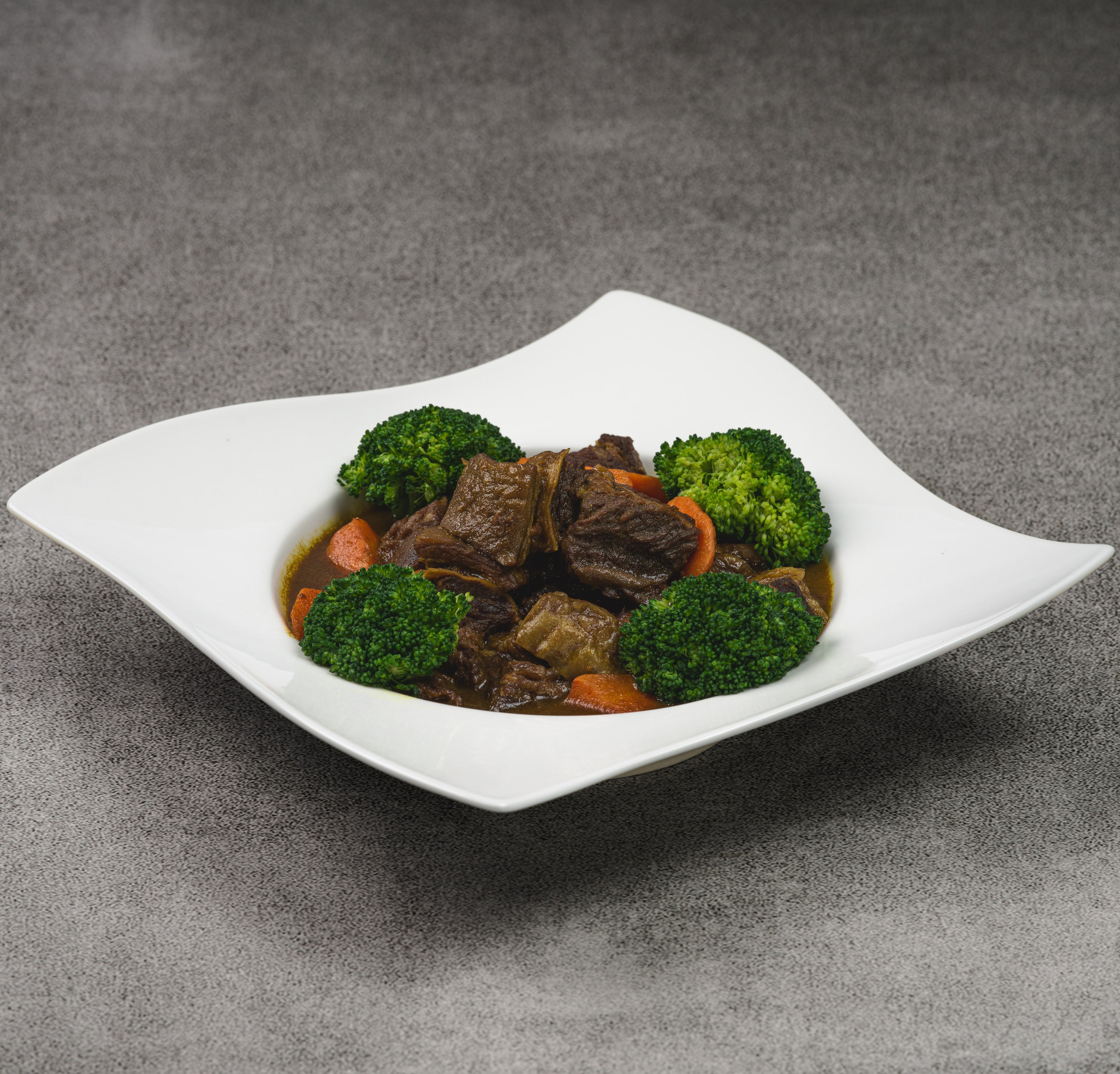 White bowl with beef and broccoli on a gray background