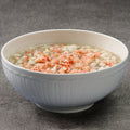 White bowl of soup with fish and crab on a gray background
