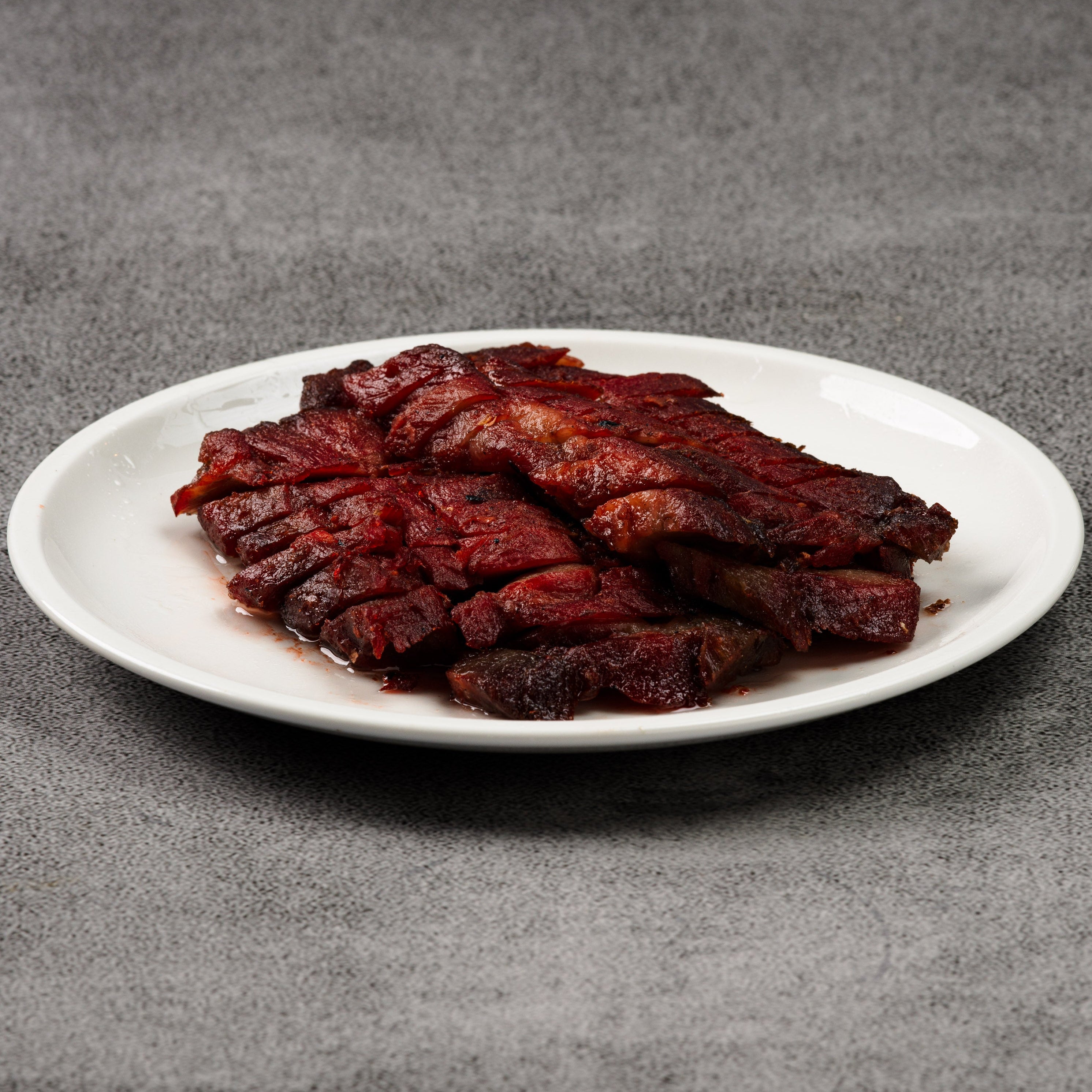Meat slices on a white plate against a gray background