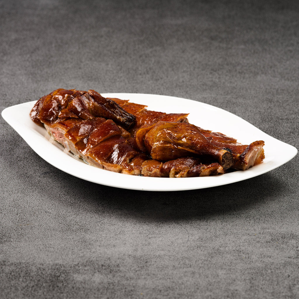 Roasted duck on a white plate with a gray background