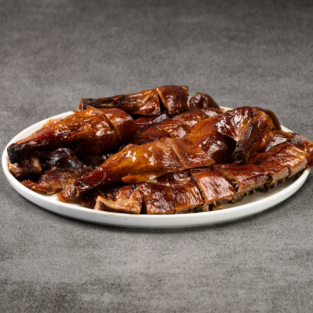 Roasted duck on a white plate with a gray background