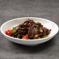 White bowl with beef and vegetable stir-fry on a gray background