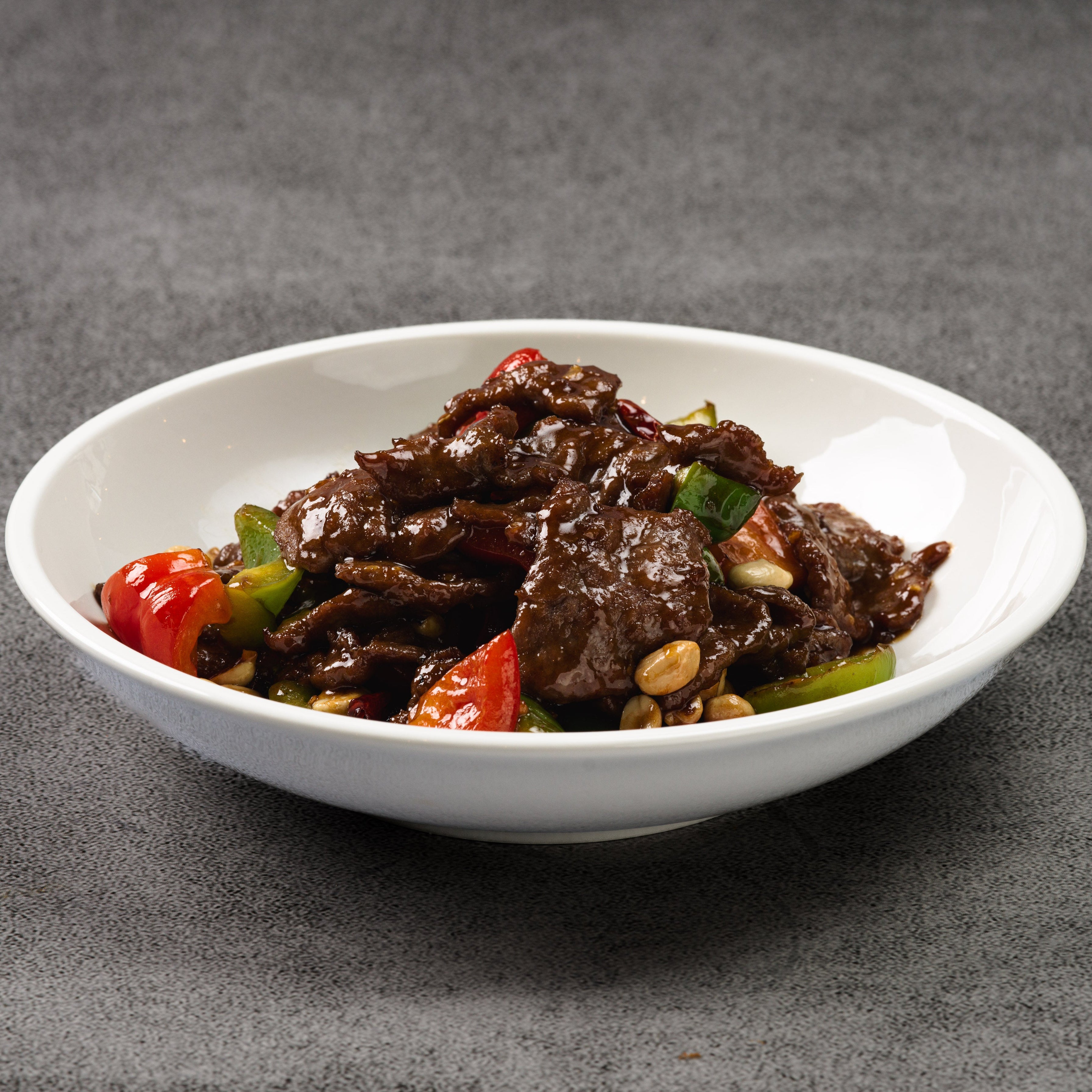 White bowl with beef and vegetable stir-fry on a gray background