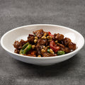 White bowl filled with a chicken stir-fry dish on a gray background