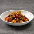 White bowl of spicy shrimp and vegetables dish on a gray background