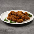 Fried pork on a white plate with green herbs on a gray background