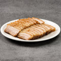 Sliced pork belly on a white plate against a gray background