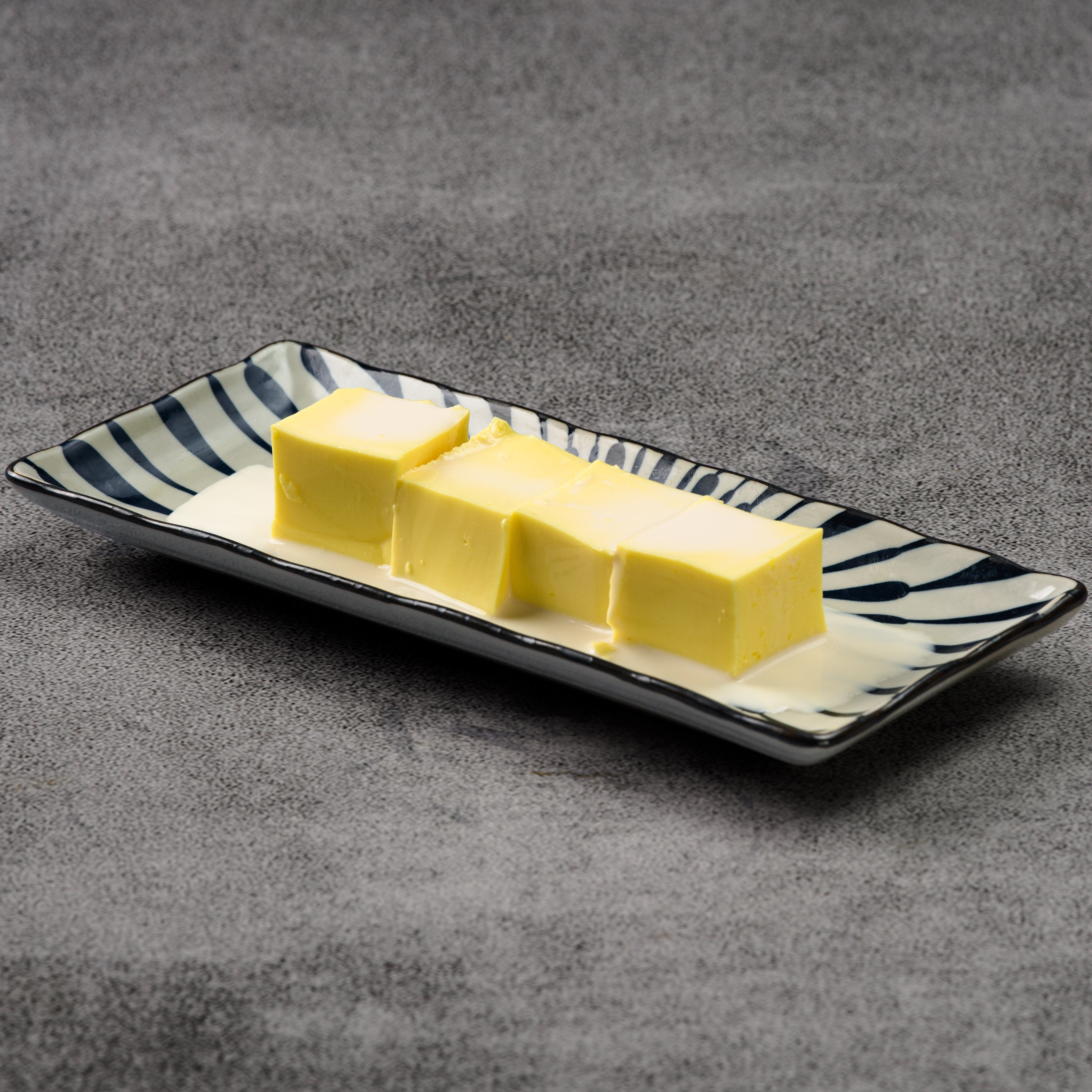 Mango pudding on a decorative rectangular plate with a zebra pattern on a gray background