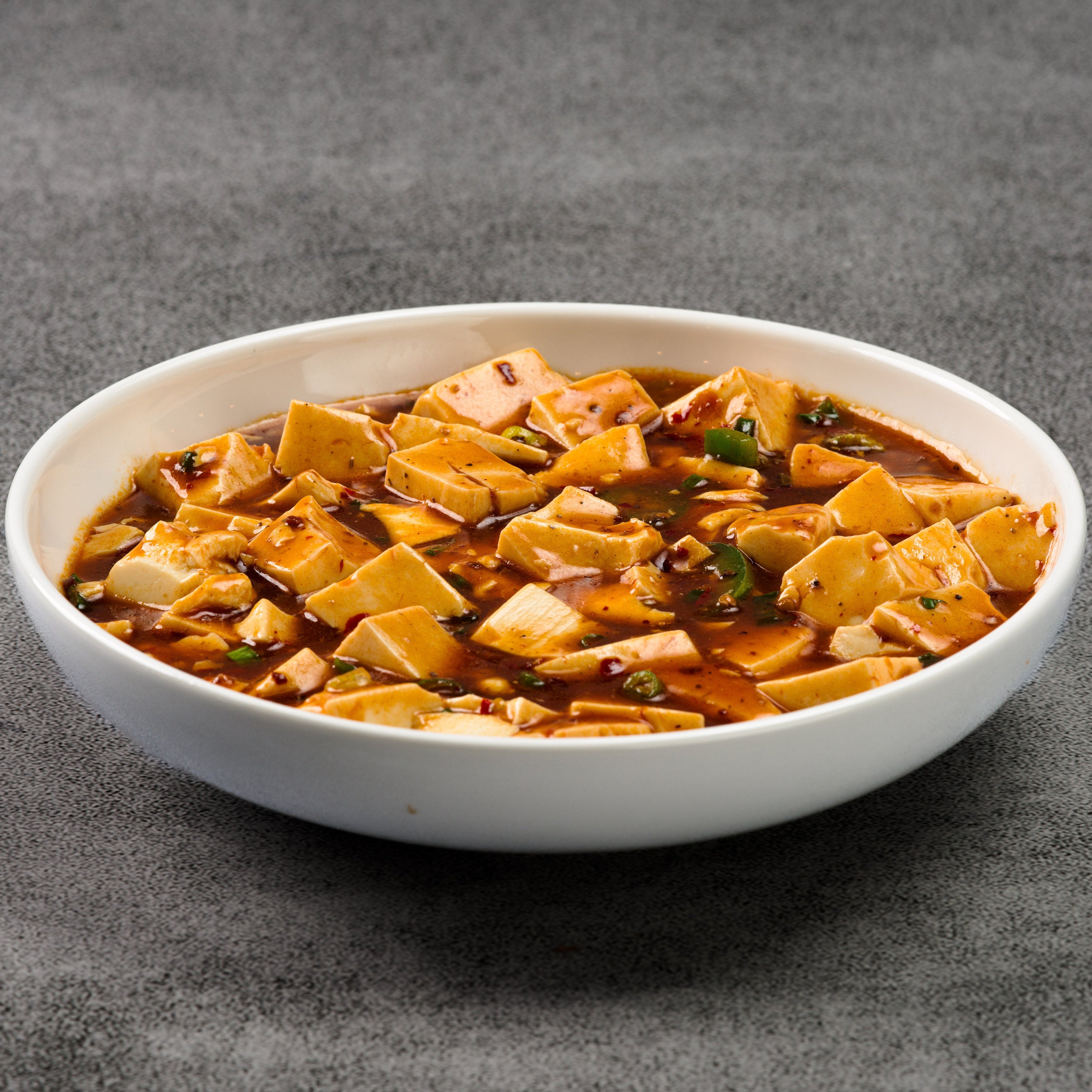Bowl of mapo tofu dish on a gray background