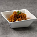 White square bowl with marinated jellyfish on a gray surface