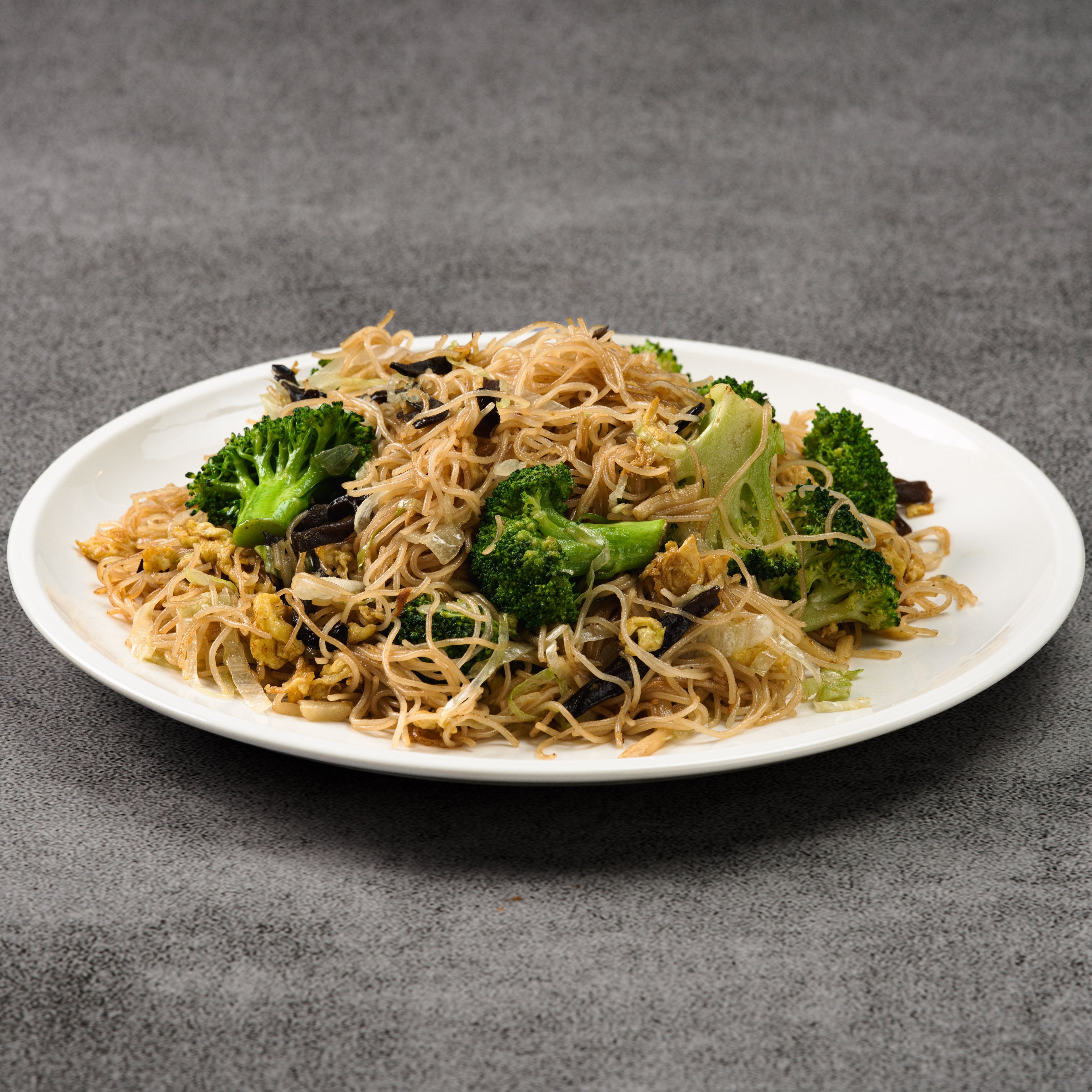 Plate of noodles with broccoli on a gray background