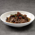White bowl with beef dish on a gray background