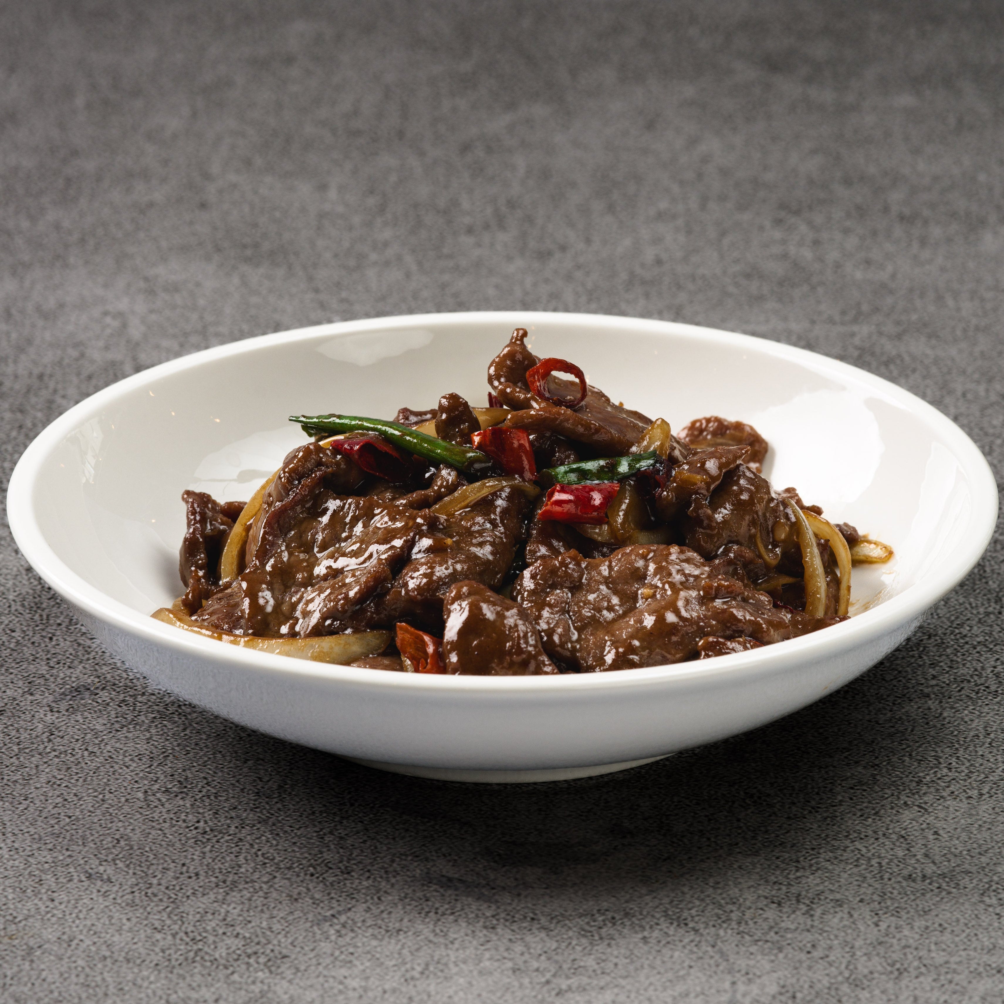White bowl with beef dish on a gray background