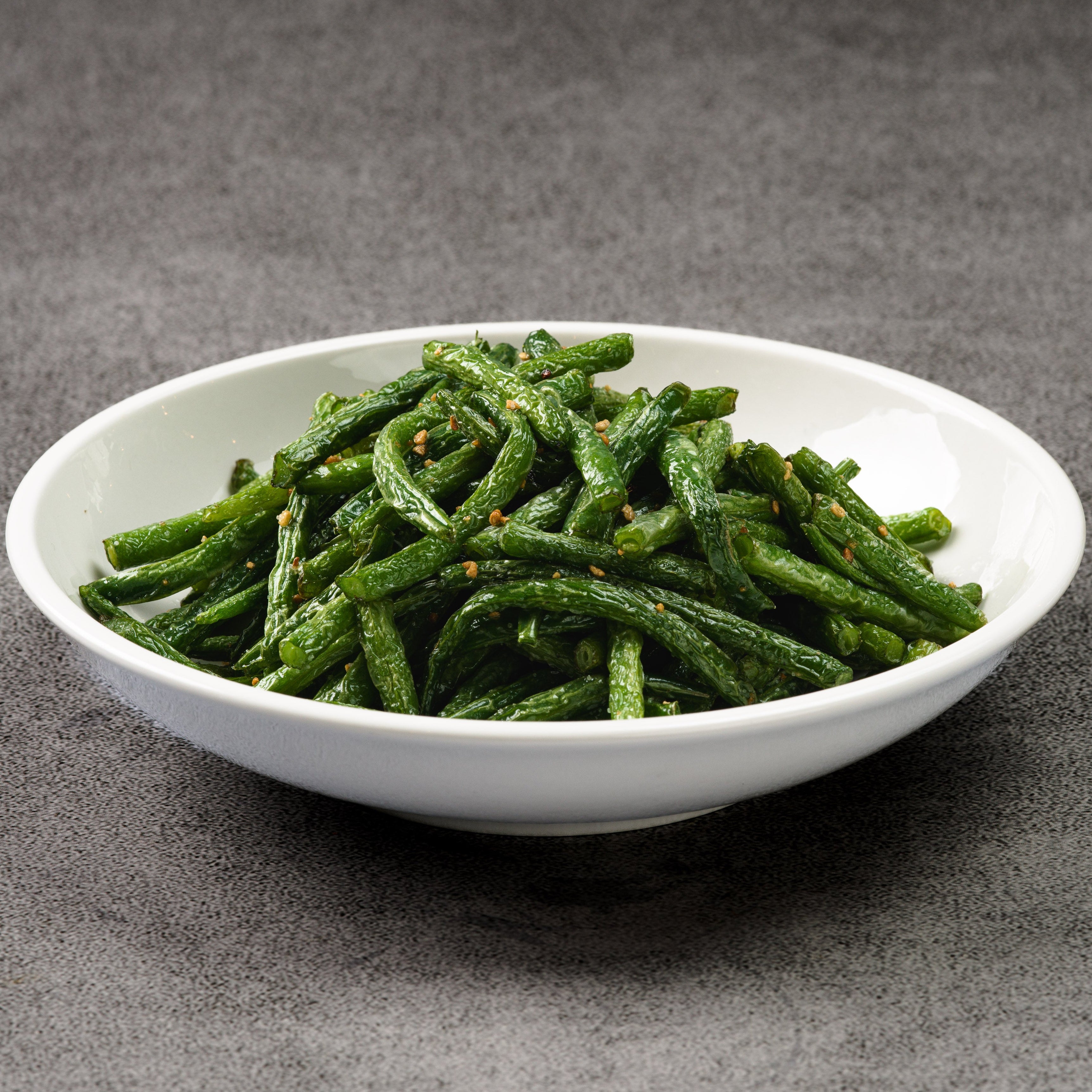 White bowl filled with green beans on a gray background