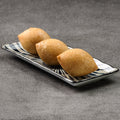 Three baked buns on a rectangular ceramic plate with a black and white pattern on a gray background