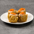 Four steamed buns with orange toppings on a white plate against a gray background