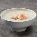 White bowl of congee with seafood on a gray surface