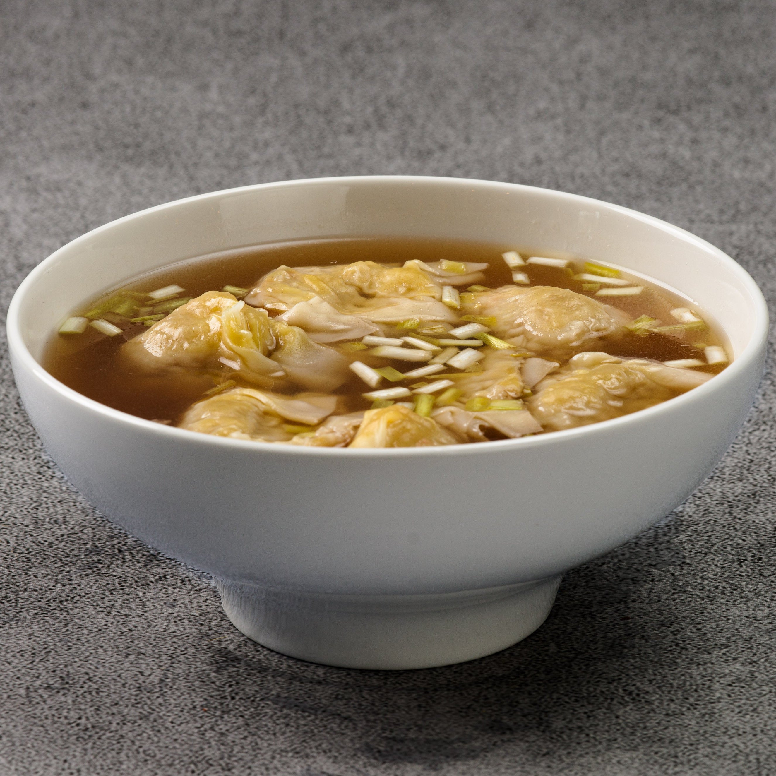 White bowl of soup with wontons on a gray background