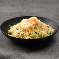Black bowl of shrimp fried rice on a gray background