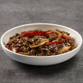 White bowl filled with a dish of beef and vegetables on a gray background