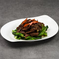Plated dish of beef and vegetables on a gray background