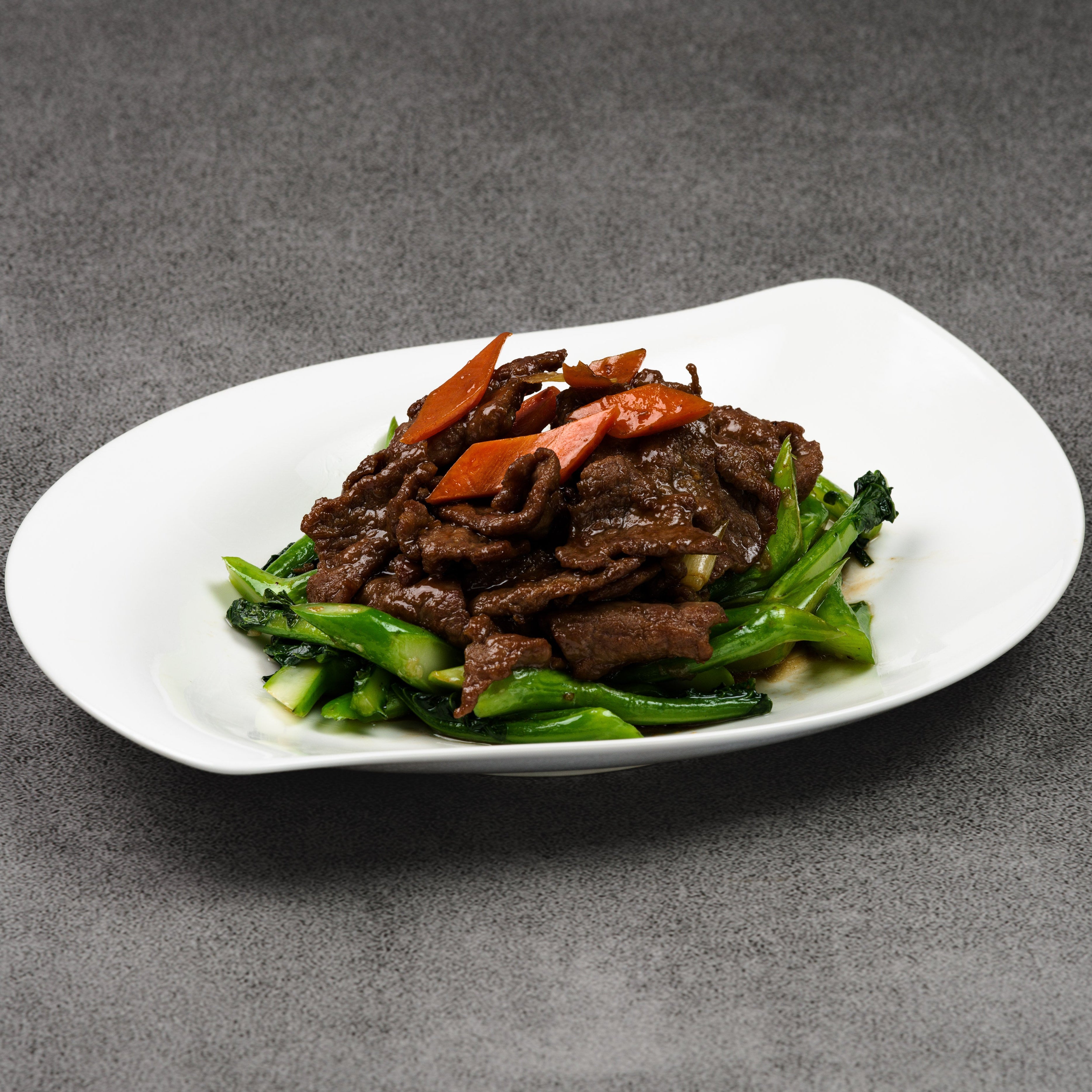 Plated dish of beef and vegetables on a gray background