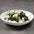 White bowl with green leafy vegetables on a gray background