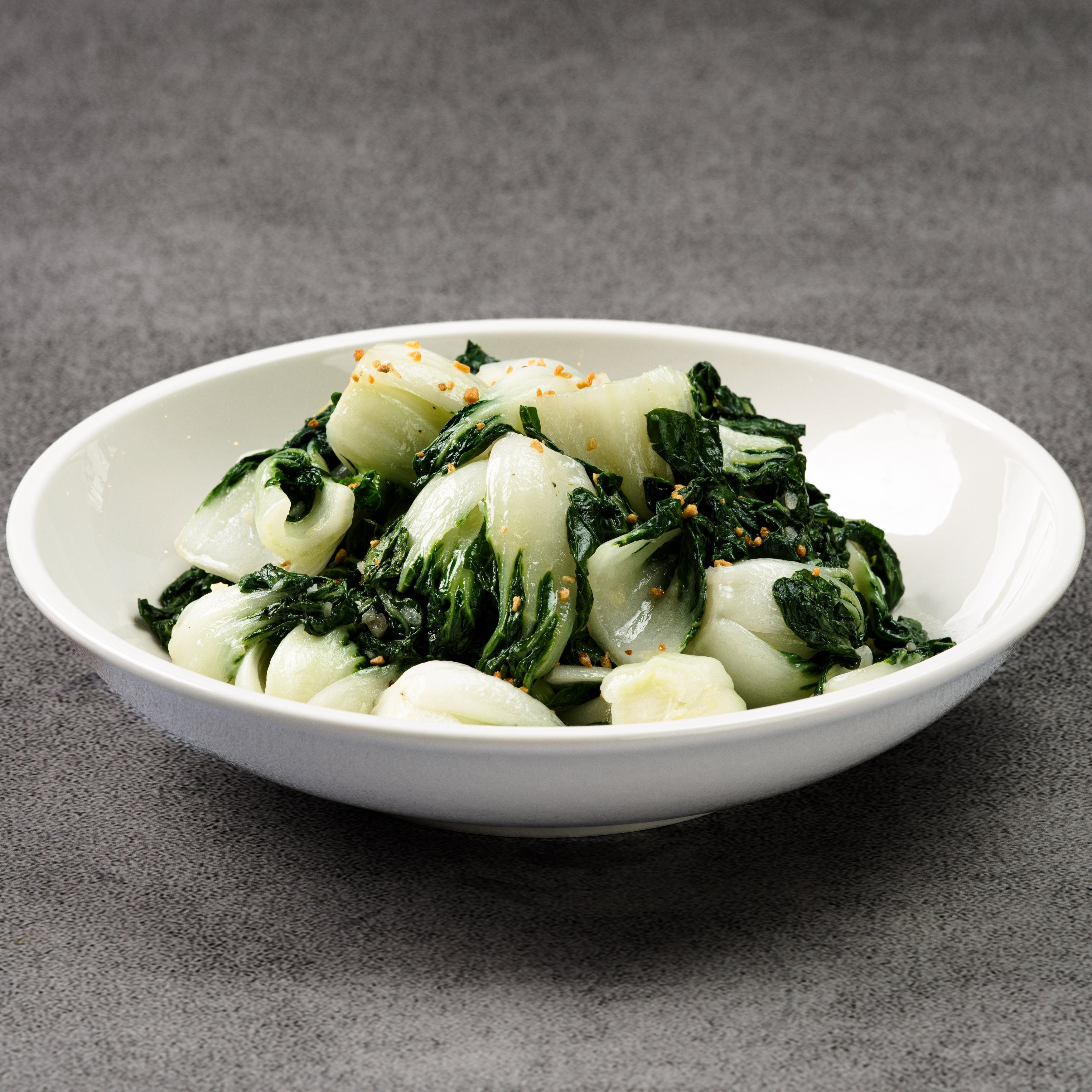 White bowl with green leafy vegetables on a gray background