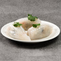 Three dumplings on a white plate on a gray surface