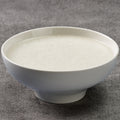 White congee in a bowl on a gray textured surface