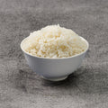 White bowl filled with rice on a gray surface