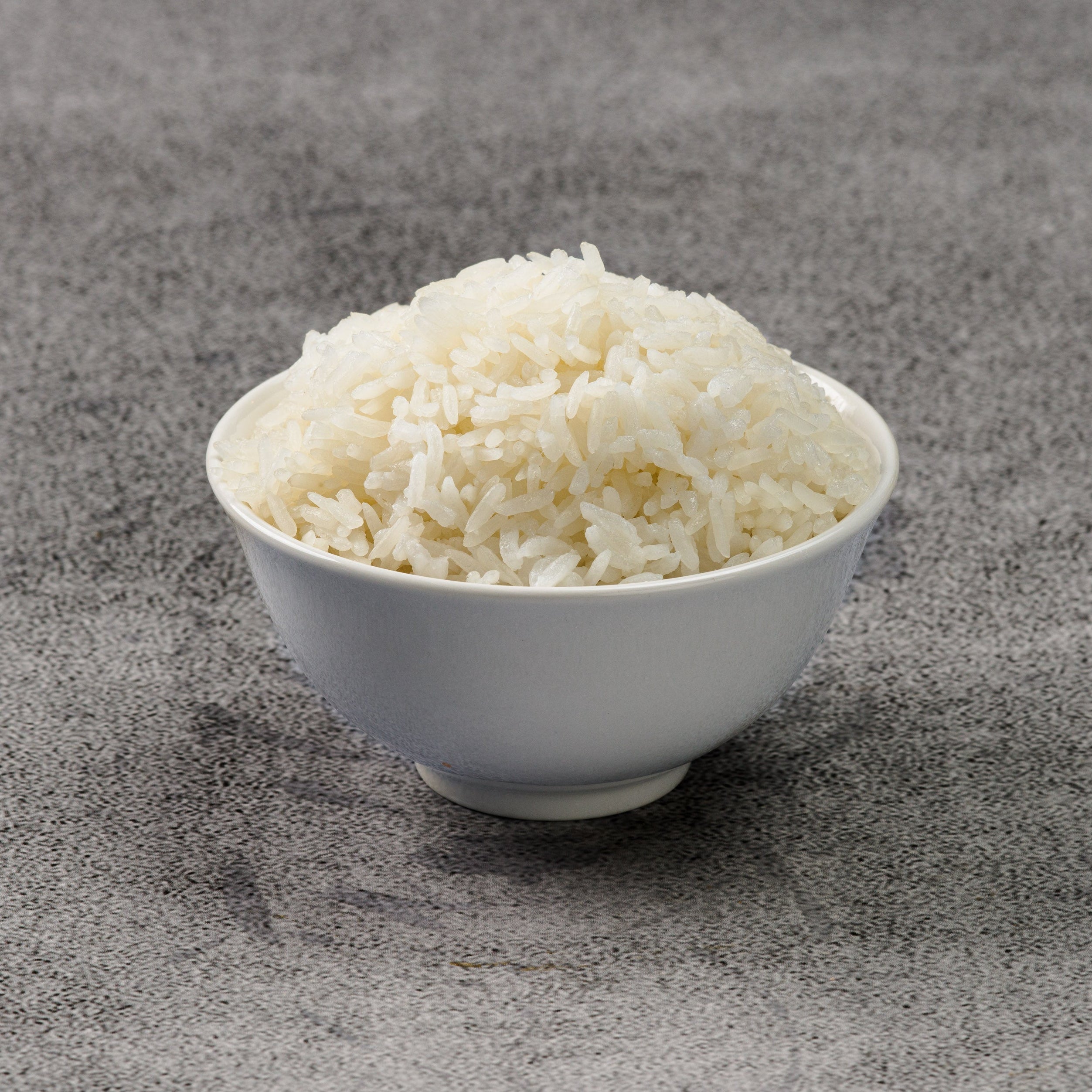 White bowl filled with rice on a gray surface