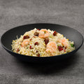 Fried rice with shrimp in a black bowl on a gray background