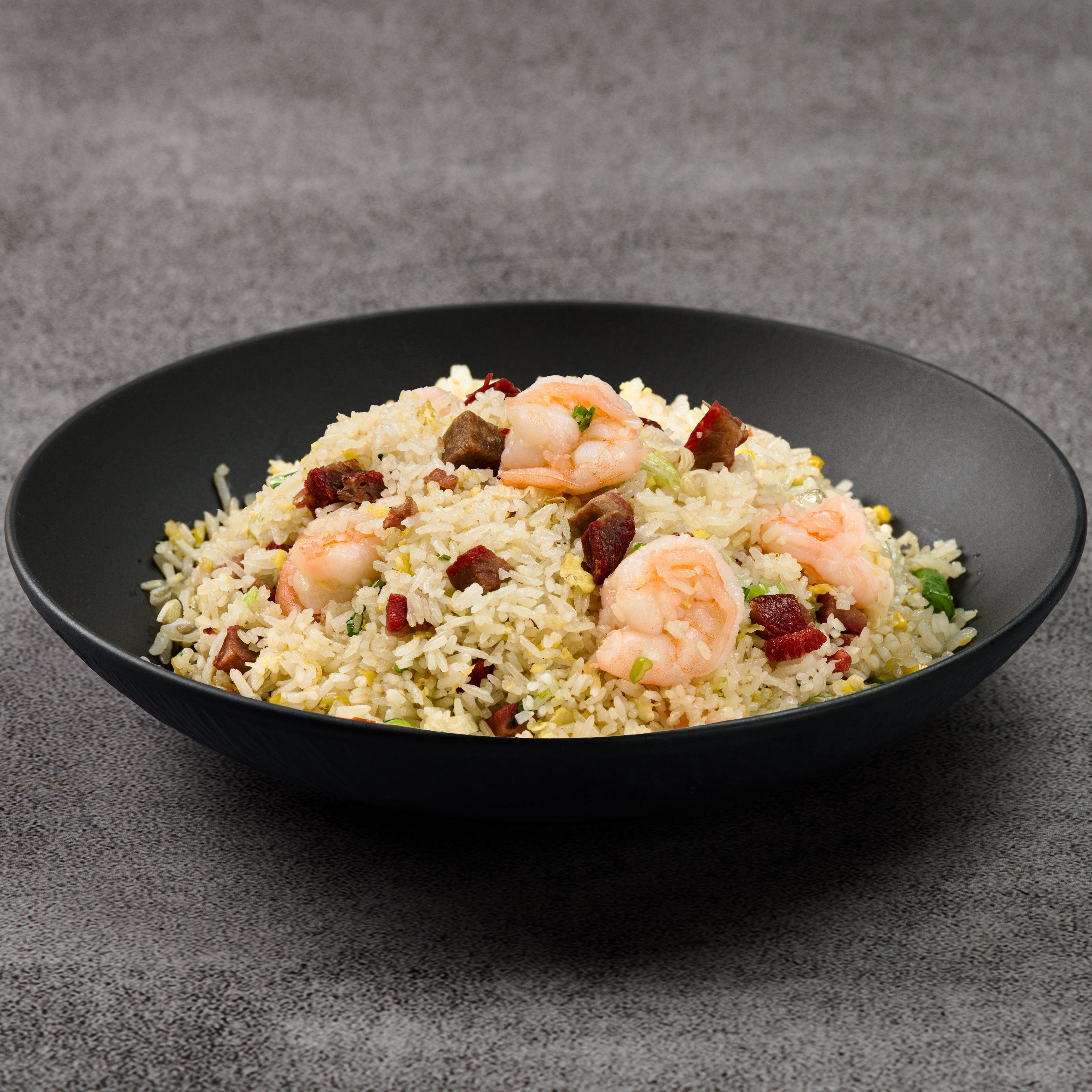 Fried rice with shrimp in a black bowl on a gray background